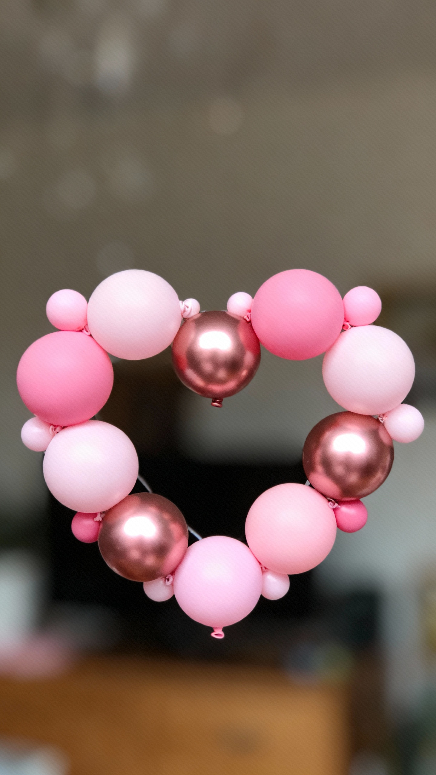Closeup of heart-shaped mini balloon wreath, matte and metallic pinks