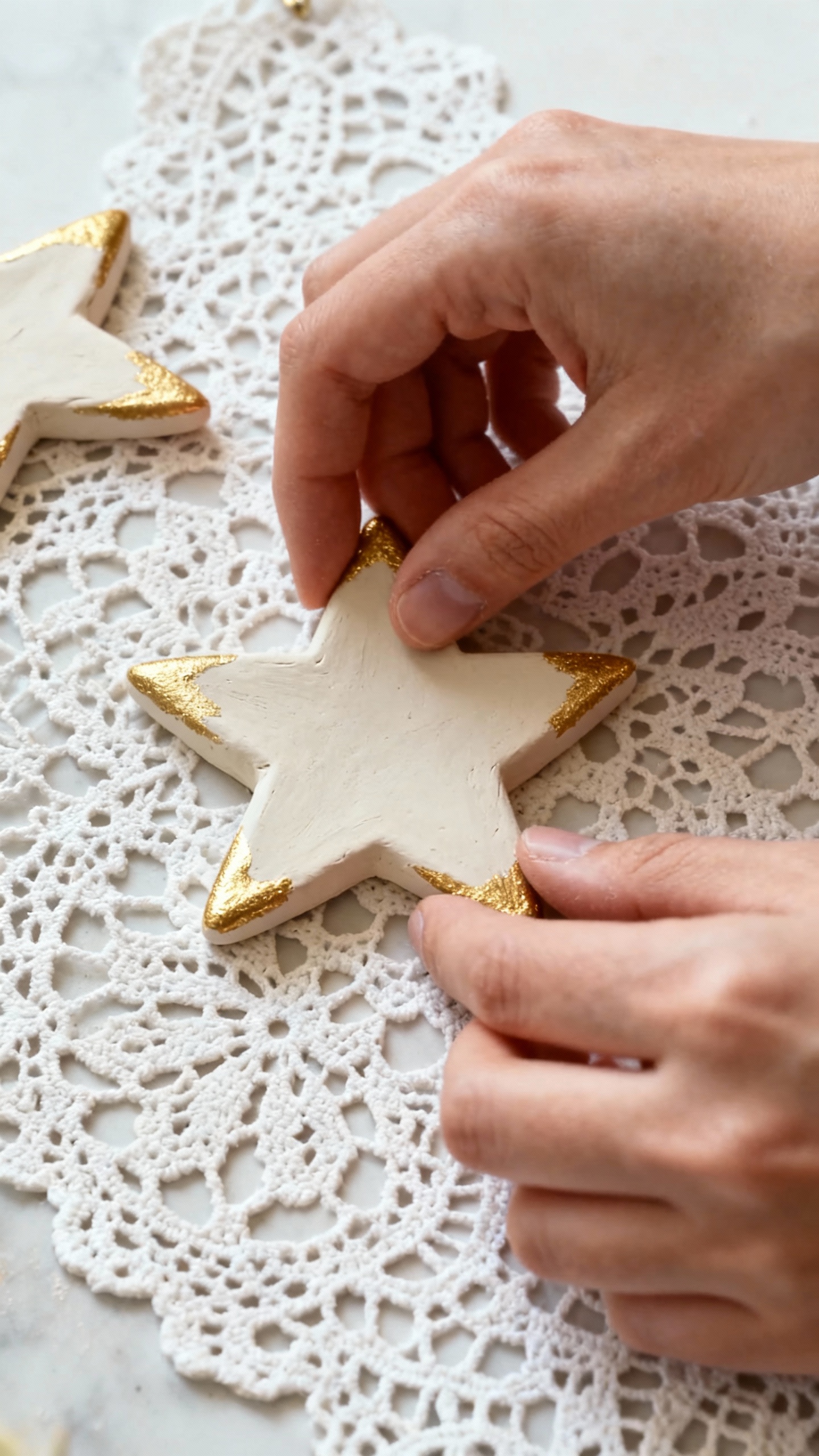 Hands stamping air-dry clay star ornament, lace texture, gold-painted edges